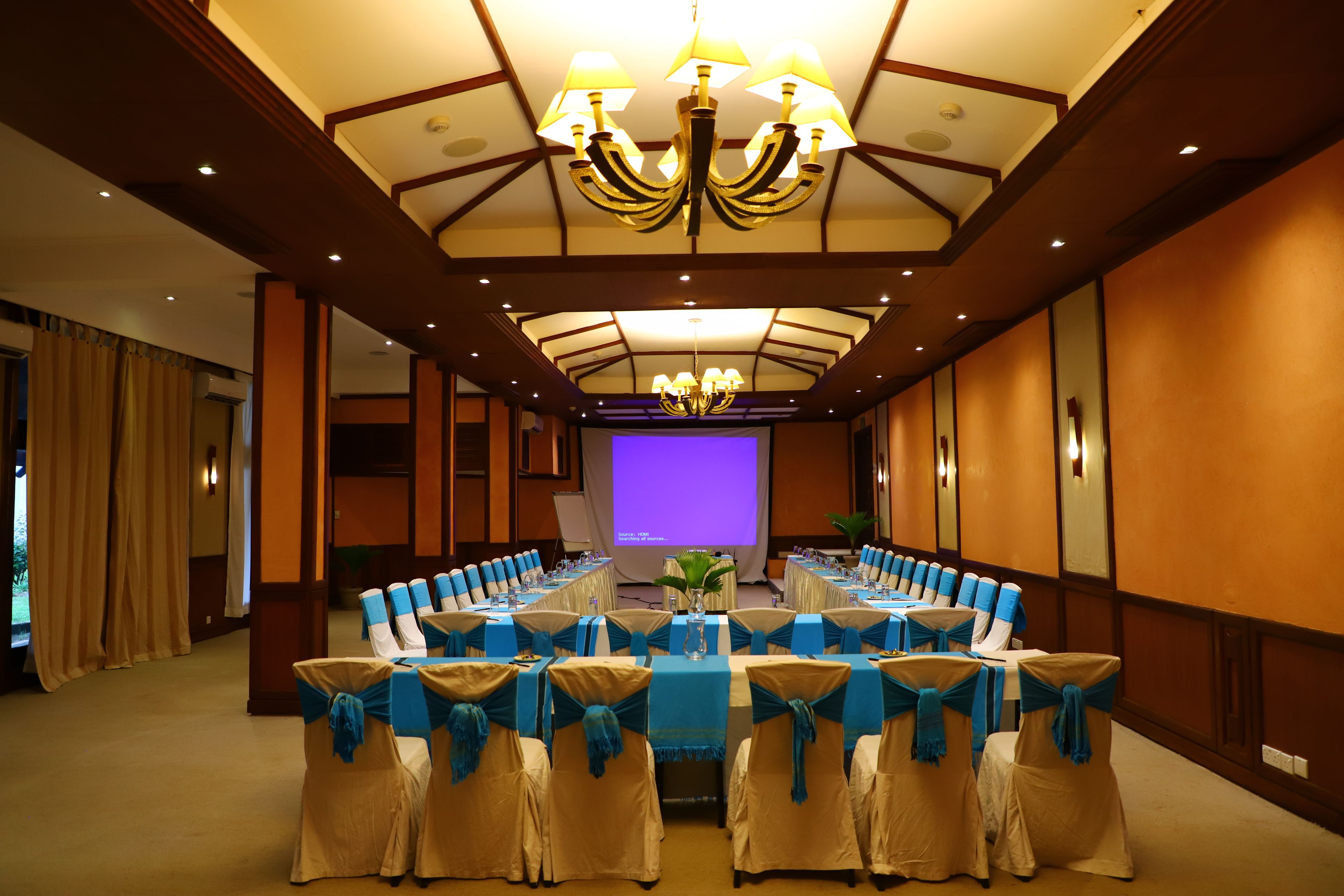 A conference room with a long table, blue chair sashes, and a chandelier.
