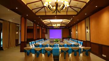 A conference room with a long table, blue chair sashes, and a chandelier.