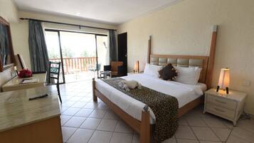 A hotel room with a bed, bedside table, nightstand, and a balcony with a chair.