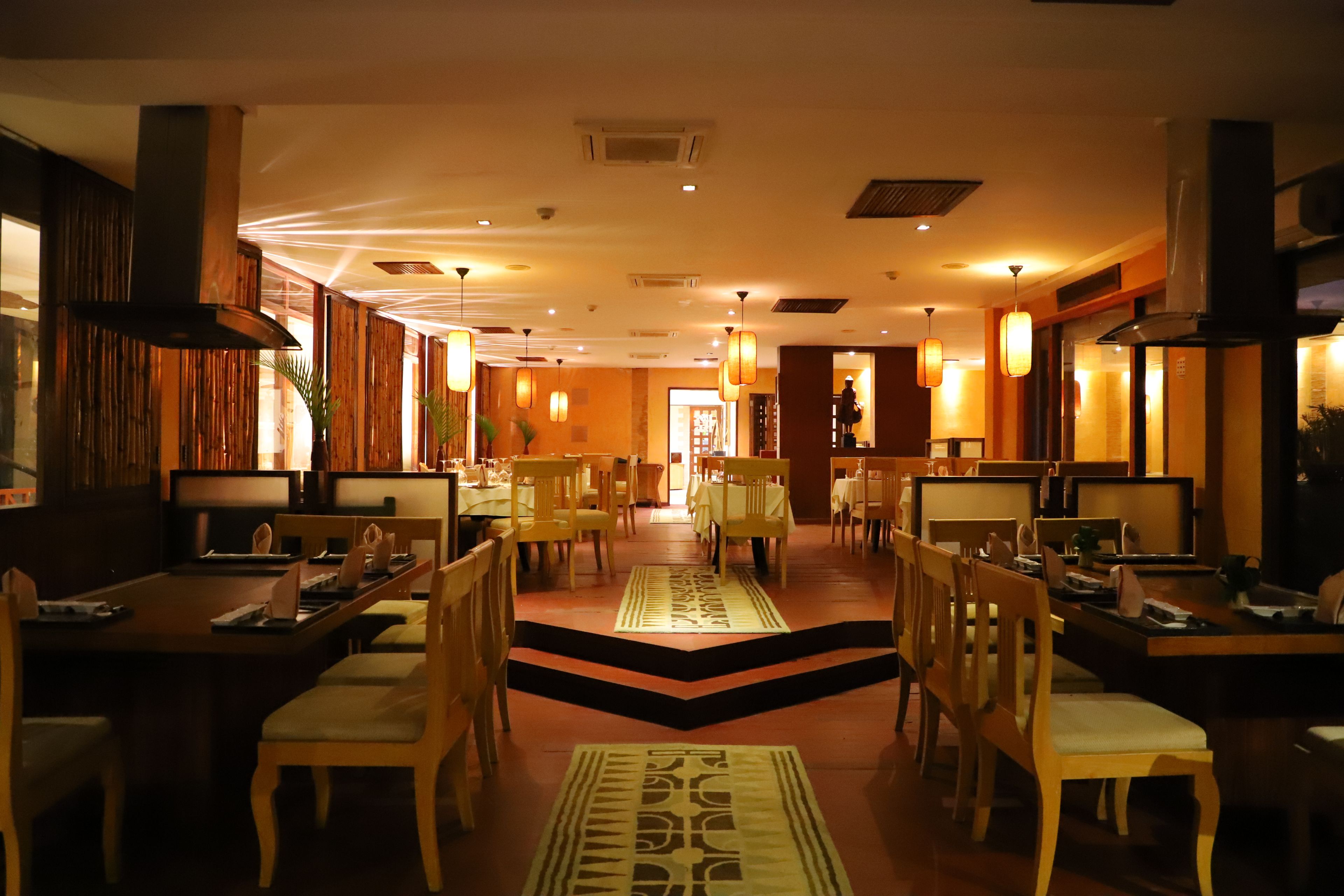 Un restaurante con muebles de madera, un pasillo central e iluminación cálida.