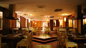 A restaurant with wooden furniture, a central aisle, and warm lighting. - Diani Reef Beach Resort & Spa (Diani Beach)