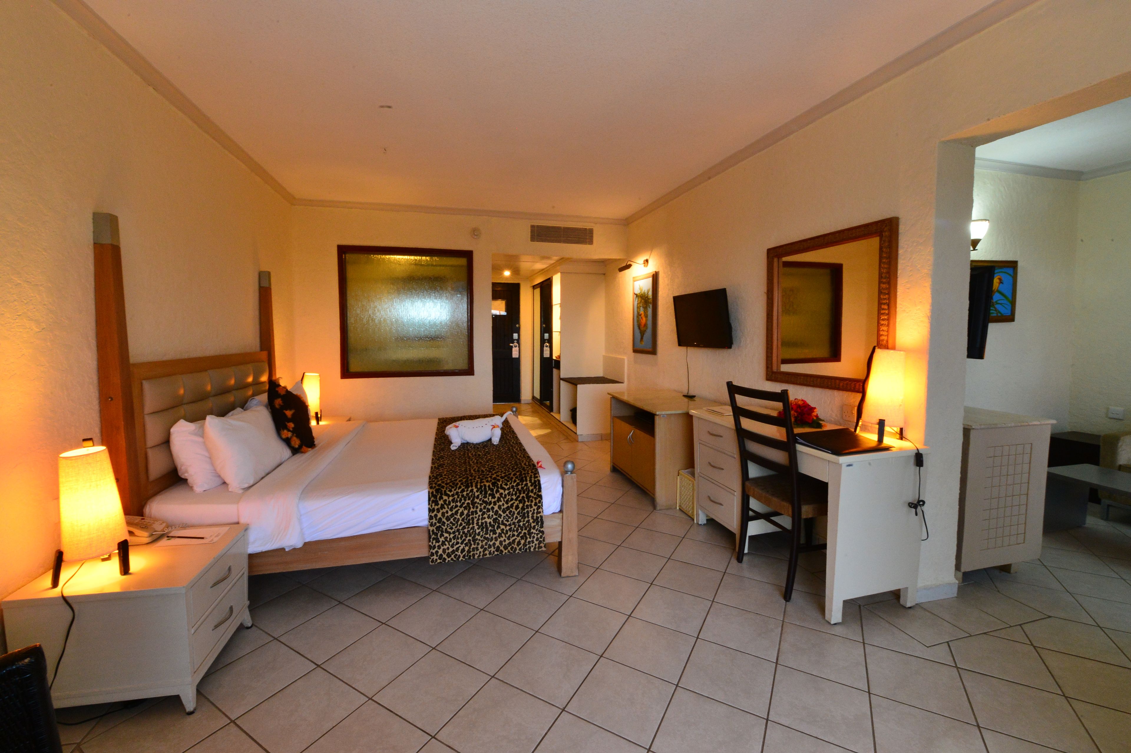 A hotel room with a bed, desk, chair, nightstand, and a TV.