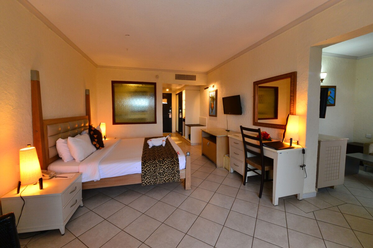 A hotel room with a bed, desk, chair, nightstand, and a TV.
