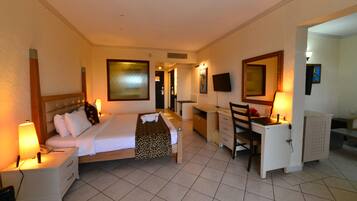 A hotel room with a bed, desk, chair, nightstand, and a TV.