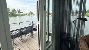 Una habitación con vistas a un lago, una mesa con sillas, una lámpara y un sofá.