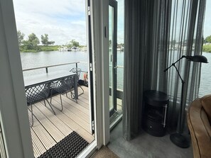 Ein Zimmer mit Seeblick, einem Tisch mit Stühlen, einer Lampe und einem Sofa.