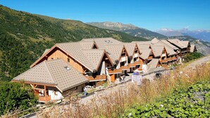 Eine Reihe Holzhütten mit geneigten Dächern vor einer Berglandschaft.