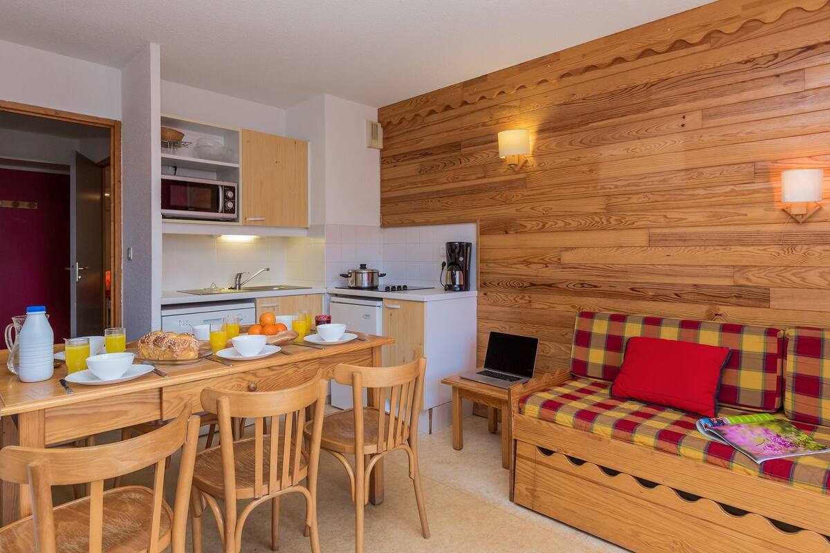 A compact kitchen with a microwave, coffee maker, and a dining area with chairs and a table.