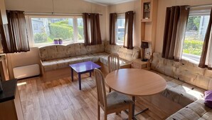 Amplia sala de estar con un conjunto de sofá, una mesa redonda y una lámpara colgante.