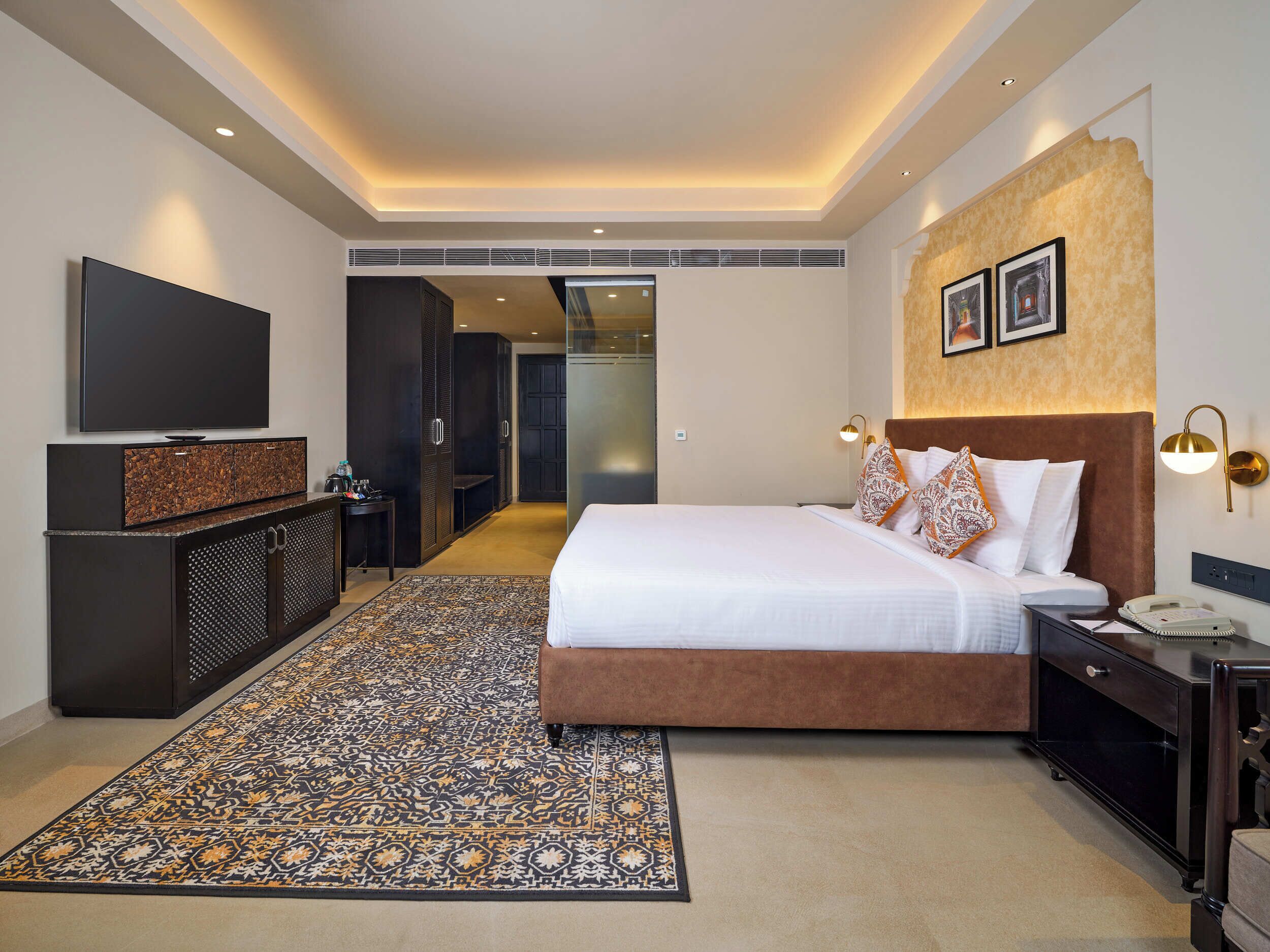 Quarto de hotel moderno com cama grande, televisão, escrivaninha e closet espaçoso.