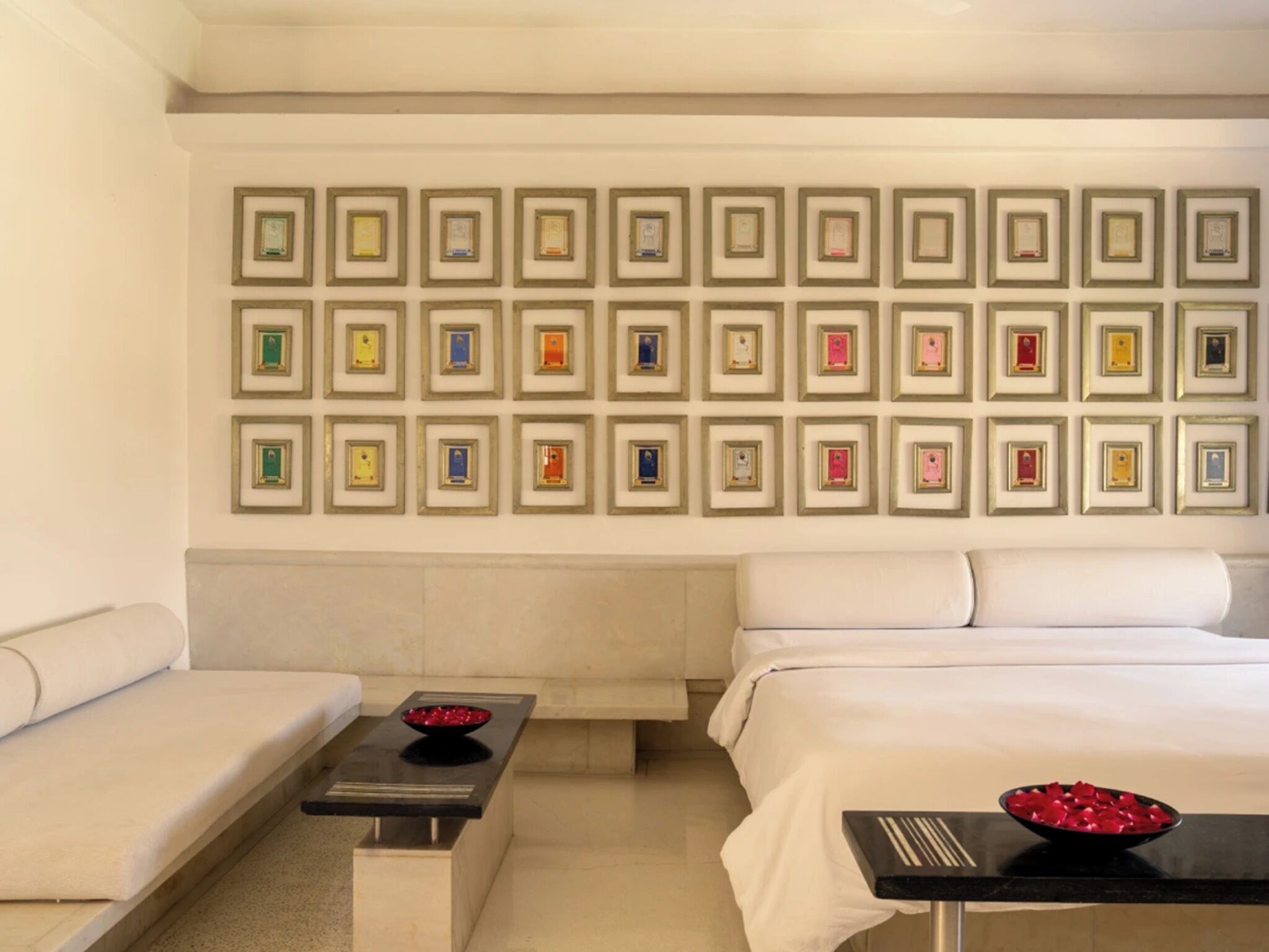 A hotel room with a bed, a sofa, a small table, and a wall decorated with framed certificates.
