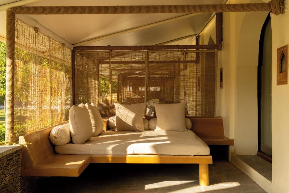 Une pièce avec un lit, une fenêtre donnant sur un beau paysage et un plafond orné de motifs tissés.