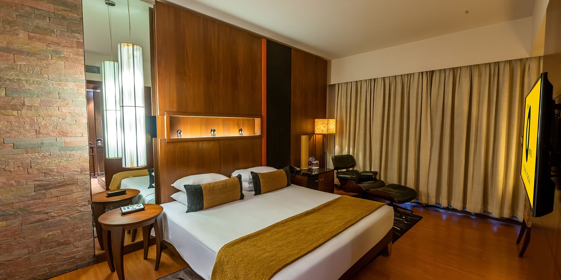 Een hotelkamer met een groot bed, een bureau, een stoel, een televisie en een spiegel.
