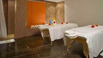 A spa room with two treatment tables, a mirror, and a tiled wall.