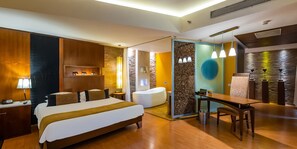 Una camera d'albergo moderna con un letto grande, bagno privato, zona pranzo e una parete decorata in pietra.