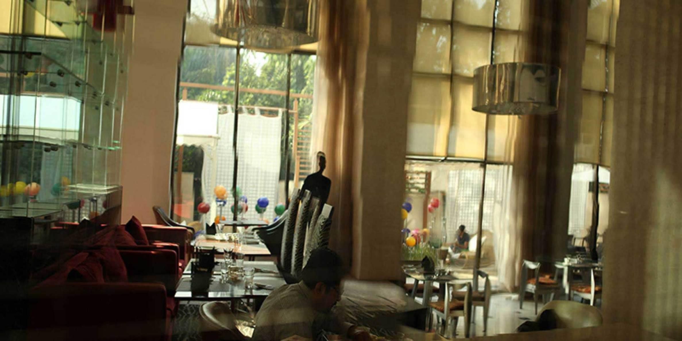 A dining area with a glass partition, a table with chairs, and a view of the outside.