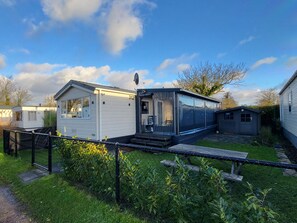 A mobile home with a fenced yard, a small shed, and a clear sky. - RBR 312 - Beach Resort Kamperland by Interhome (Kamperland)
