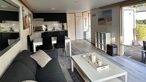 A modern living room with a sofa, a coffee table, and a kitchen area visible through an open door. - RBR 1654 - Beach Resort Kamperland by Interhome (Kamperland)