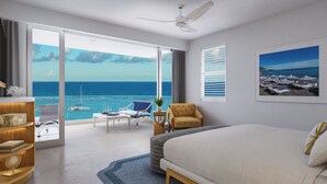 A hotel room with a large bed, a desk, a chair, a small table with a plant, and a view of the ocean.