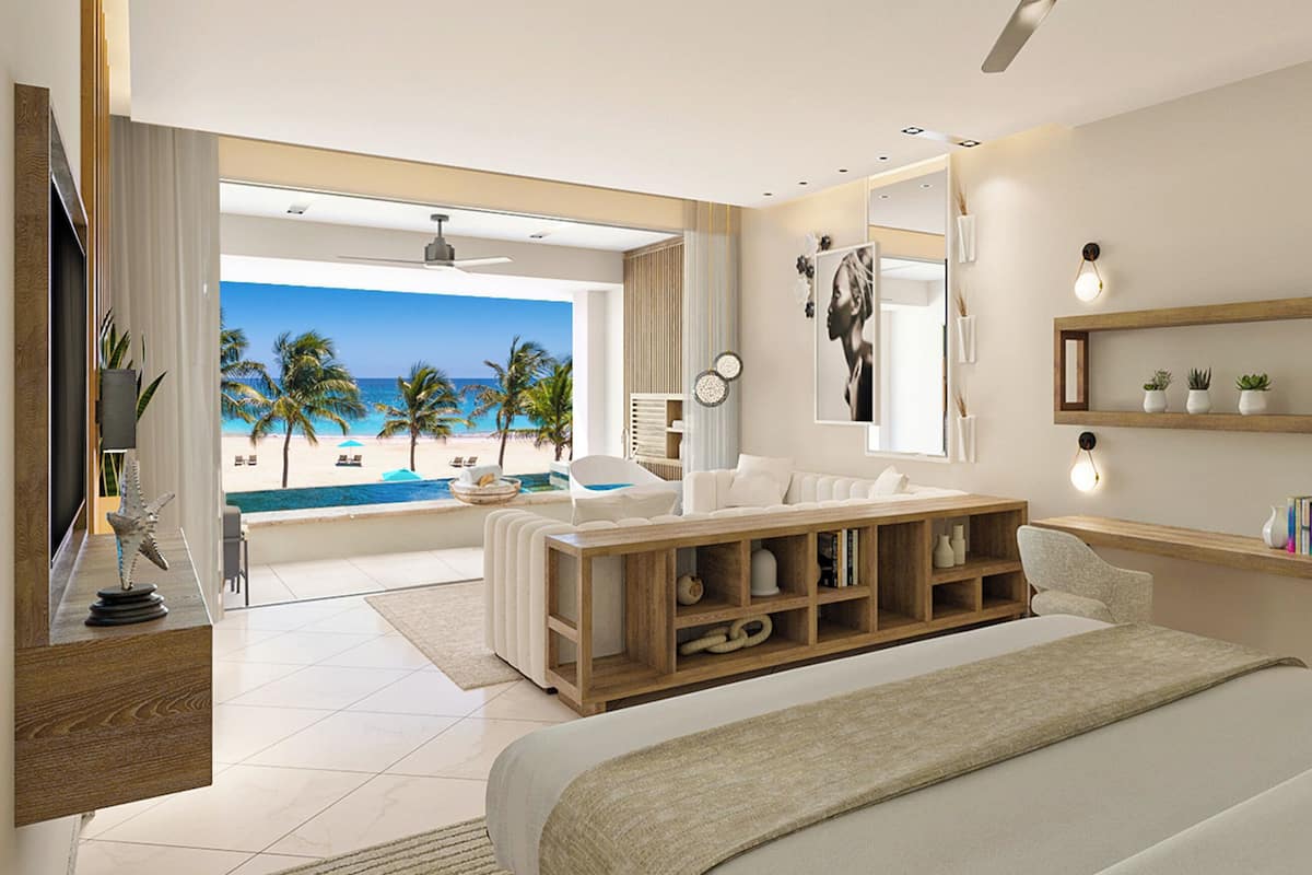 Un dormitorio moderno con una cama grande, una mesita de madera, vista a la playa y un estante con objetos decorativos.