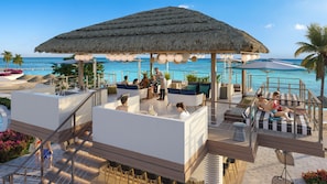 A rooftop bar with a thatched roof, outdoor seating, and a view of the ocean. - Sandals Dunn's River Falls (Ocho Rios)
