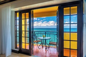 A balcony with a view of the ocean, a table with chairs, and a decorative vase. - Sandals Dunn's River Falls (Ocho Rios)