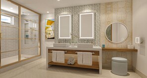 A modern bathroom with a glass shower enclosure, a wooden vanity with a sink, and a large mirror.