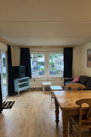 Ein Wohnzimmer mit Holztisch, Fernseher und Sofa.