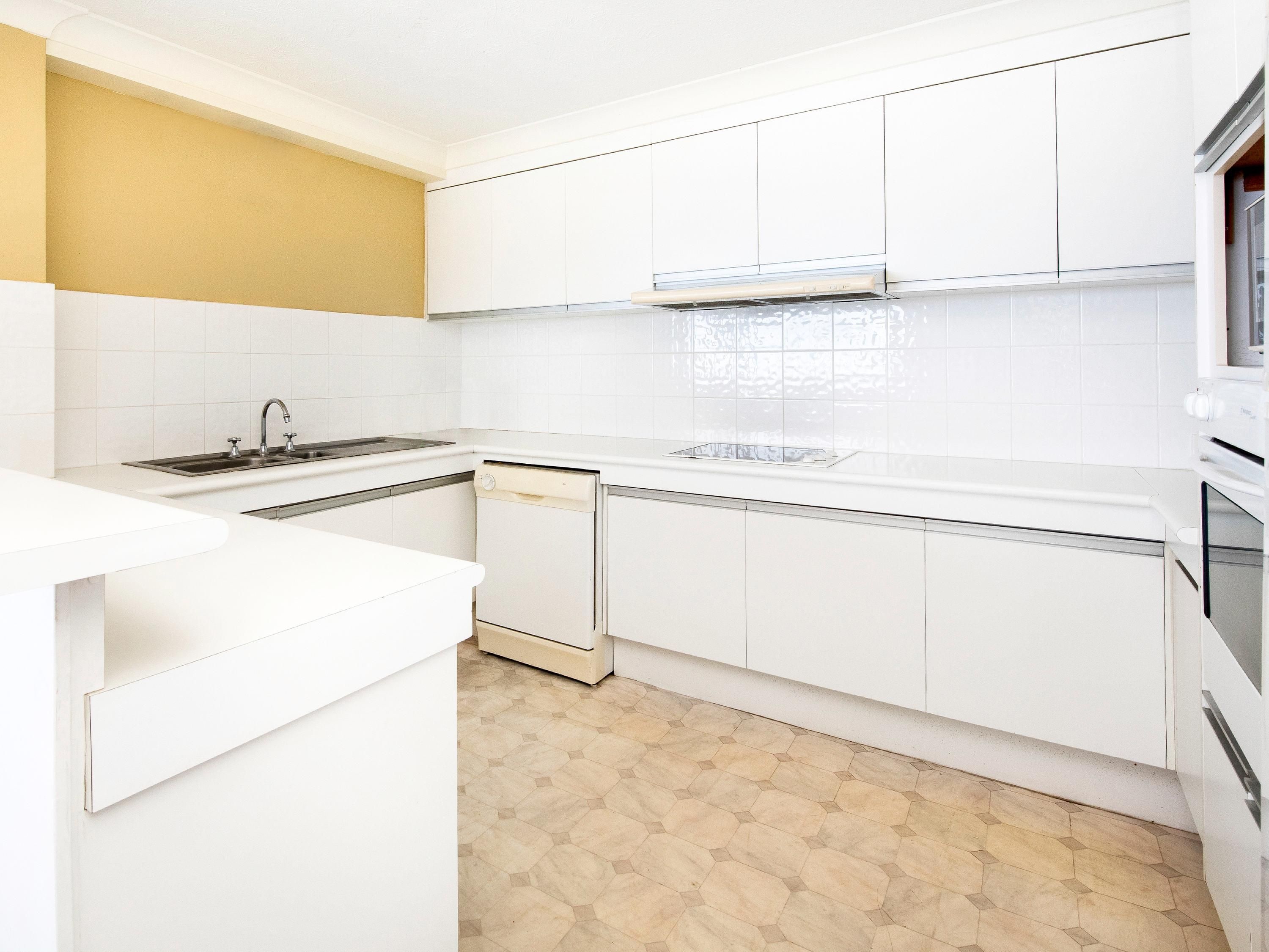 A kitchen with white cabinets, a dishwasher, a stove, and a microwave.