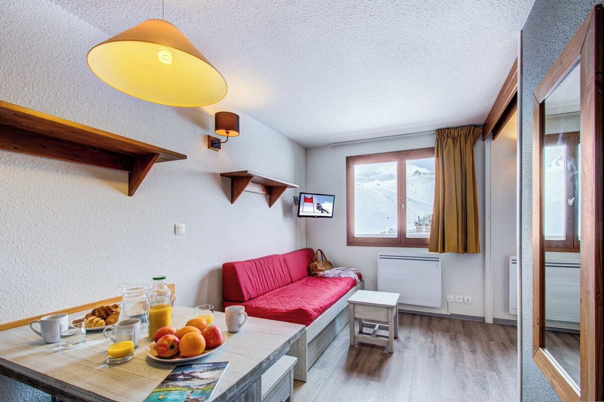 Una habitación acogedora con cama, una mesa con desayuno, televisión y ventana con cortinas.