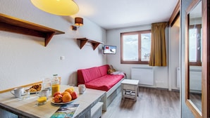 A cozy room with a bed, a table with breakfast, a TV, and a window with curtains. - Résidence Le Borsat IV - Vacanceole (Tignes)