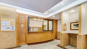 A reception area with wooden paneling, a reception desk, and a stone-tiled floor. - Résidence Le Borsat IV - Vacanceole (Tignes)
