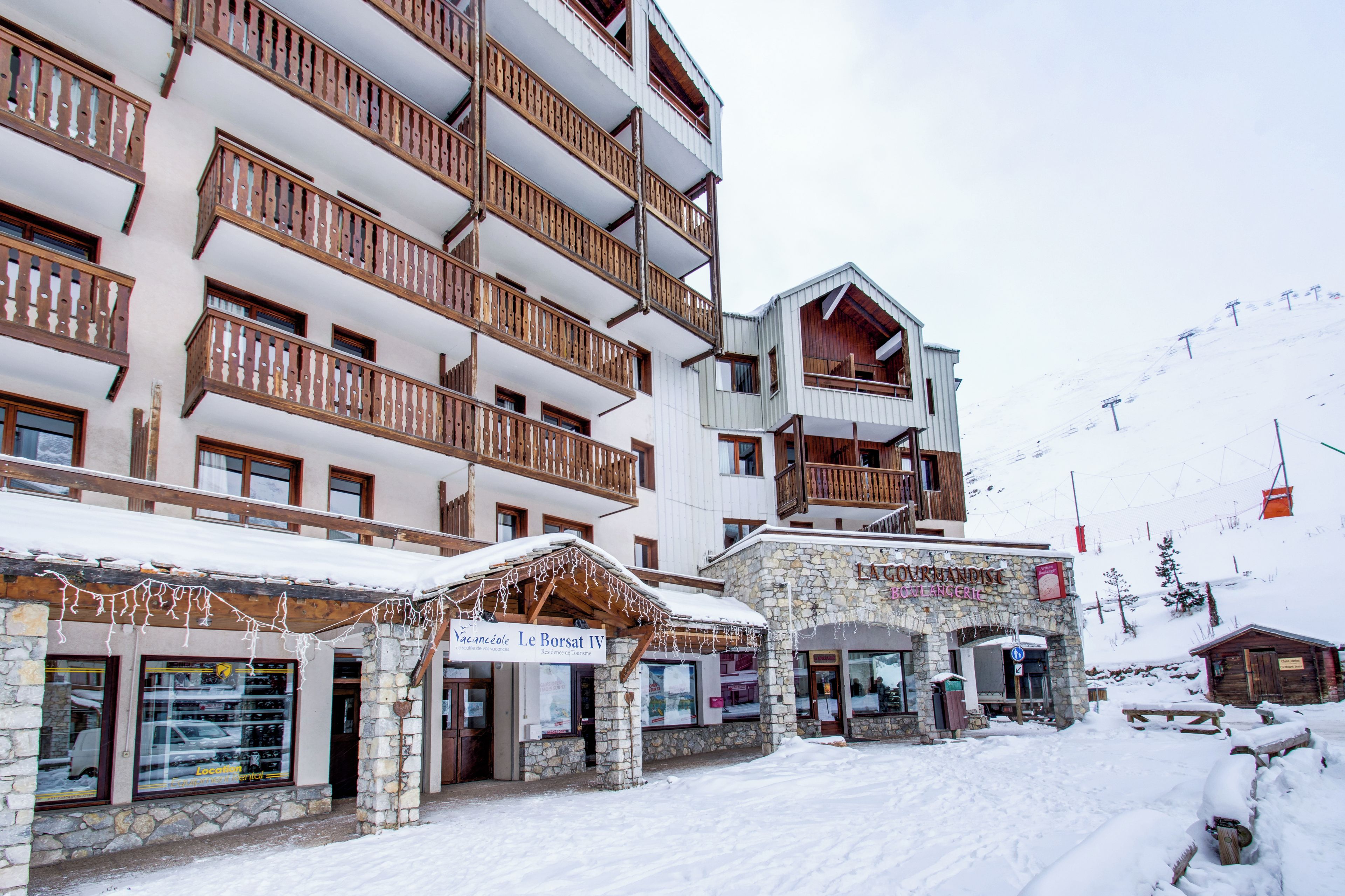 A multi-story hotel with balconies, a stone facade, and a sign for 'Le Borsat IV.'