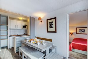 Una cocina compacta con microondas, una mesa de comedor con bancos y espacio para el desayuno.