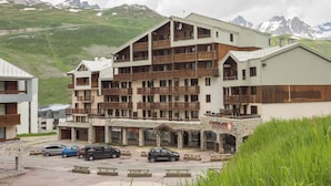A multi-story hotel with balconies, a stone facade, and a view of mountains. - Résidence Le Borsat IV - Vacanceole (Tignes)