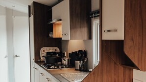 Eine kleine Küche mit Holzschränken, einem Herd und einer Kaffeemaschine.