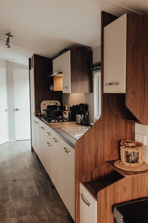 Eine kleine Küche mit Holzschränken, einem Herd und einer Kaffeemaschine.