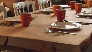 Ein Holztisch mit Stühlen, Tellern und roten Tassen.