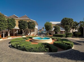 A courtyard with a central fountain, surrounded by well-manicured hedges and a paved walkway. - Melia Braco Village (Rio Bueno)