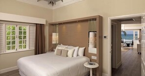 A hotel room with a large bed, a small bedside table, a mirror, and a view of the ocean. - Melia Braco Village (Rio Bueno)