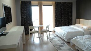 Une chambre d’hôtel équipée d’un bureau, de deux lits, d’une télévision et d’une fenêtre avec des rideaux.