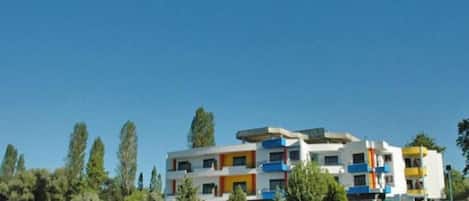 A multi-story building with balconies, a flat roof, and a clear blue sky.