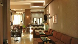 Un hall d’hôtel comprenant un comptoir d’accueil, un espace salon et une personne travaillant au comptoir.