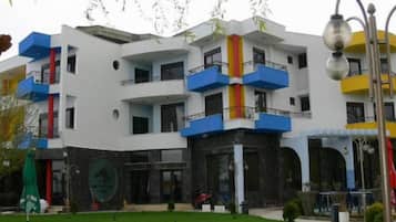 Un edificio de varios pisos con balcones, un letrero circular y un césped verde.
