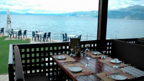 Un espace repas avec des tables disposées pour accueillir quatre personnes, donnant sur un plan d’eau.