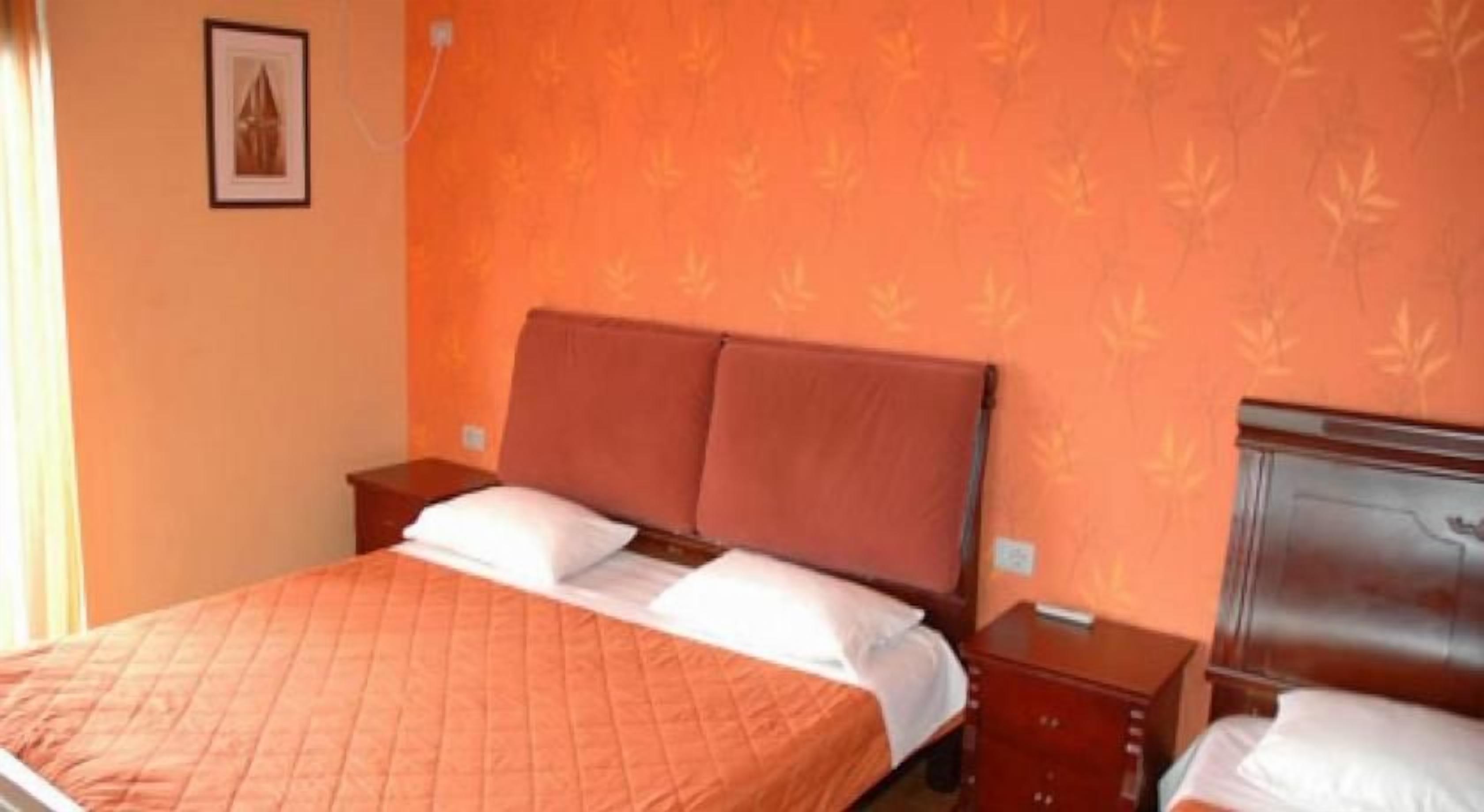 A hotel room with a bed, two nightstands, a wooden headboard, and a patterned wall.