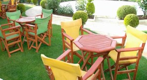 Mobiliario de madera exterior con sillas y una mesa, dispuesto en un césped.