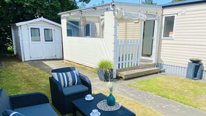 A caravan with a patio area, including outdoor furniture and a small table with a cup and saucer. - RBR 642 - Beach Resort Kamperland by Interhome (Kamperland)