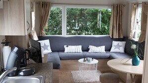 A compact living space with a kitchenette, a sofa set, a dining table, and a view of greenery outside. - RBR 642 - Beach Resort Kamperland by Interhome (Kamperland)