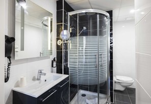 A modern bathroom with a glass-enclosed shower, a white sink, and a toilet.